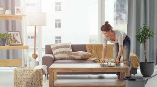 Young woman cleaning and organizing her living room space. | Merry Maids®