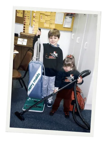 Childhood photo of Drew and Demi, second-generation owners of Merry Maids of Lancaster County, with a vintage Merry Maids vacuum.