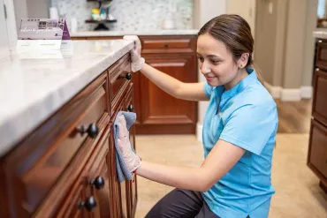 Merry Maids cleaner wiping cabinets