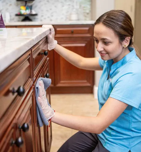 Merry Maids cleaner wiping cabinets